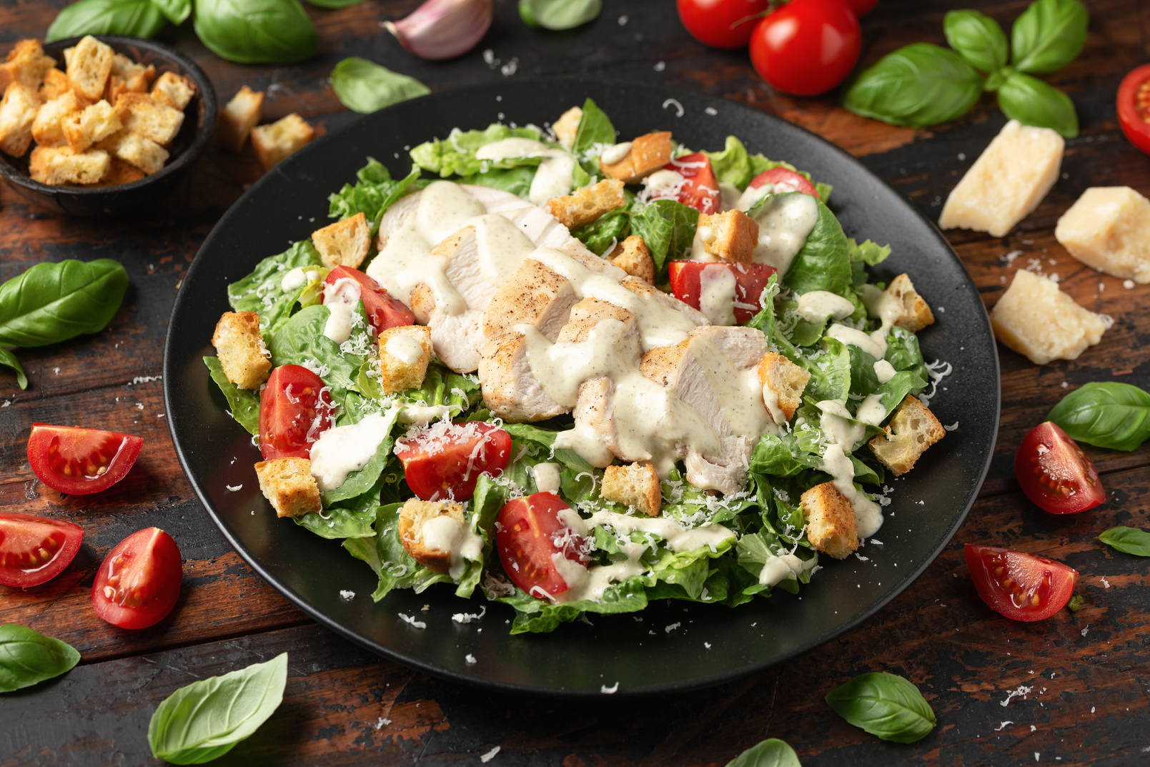 A delicious chicken caesar salad with parmesan cheese, tomatoes, croutons and dressing